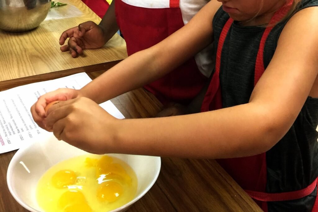 Egg cracking practice - as girl cracks egg shell and drops egg into bowl for breakfast burrito recipe